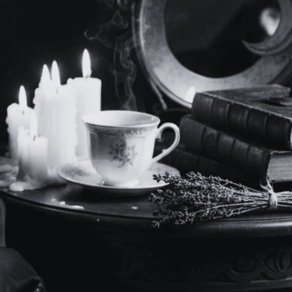Tasse de thé posée sur une table avec des bougies allumées, des livres anciens et un bouquet de lavande. Ambiance poétique et introspective du Journal des Intuitives, signé Lune & Moustache.
